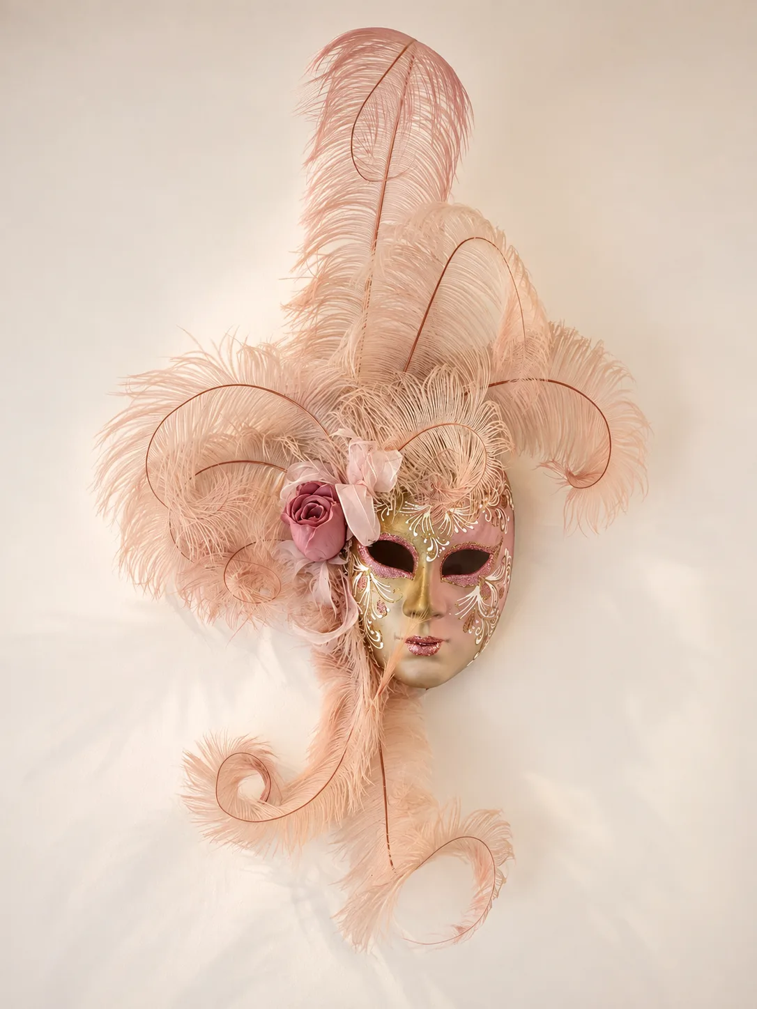 Masque vénitien à plumes rose poudré décorant le salon A l'Ongle du Lac